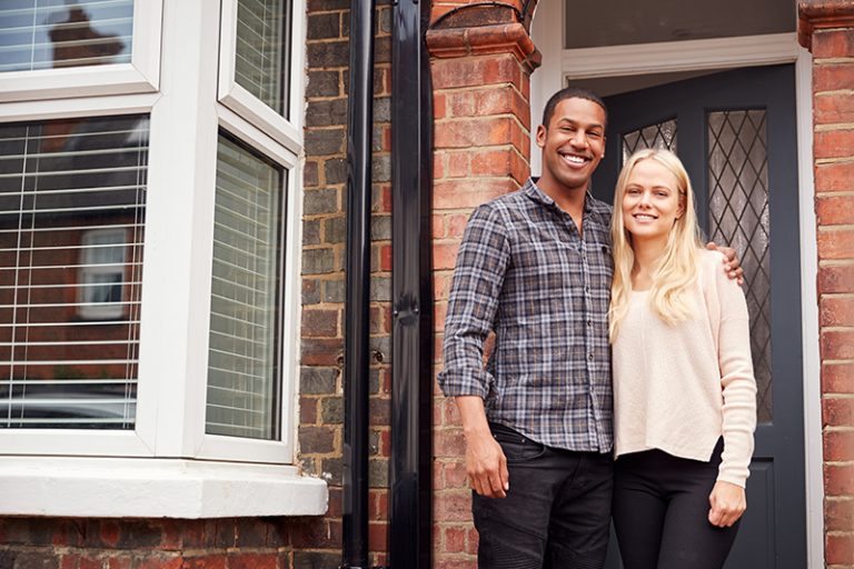 Young couple standing in front of a Victorian house