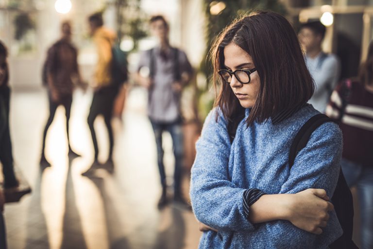 Sad student with glasses in school hallway