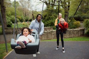 Two women push children on swings