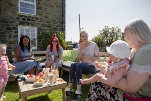 Adults and children sitting outside having a picnic together in summer.