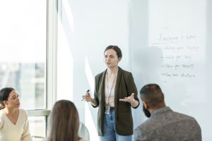 Young woman leading a meeting in front of a whiteboard