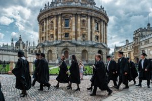 Students walk past Radcliffe Camera during the Graduation Ceremony in Oxford, England, UK on a cloudy day.