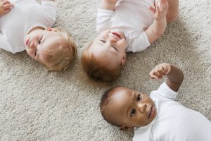 Three babies lying on the floor